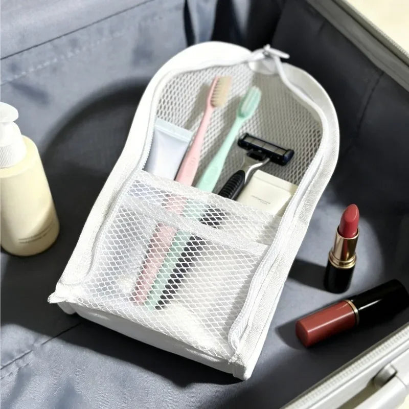 A white mesh standing toiletry bag filled with travel essentials, positioned inside a suitcase.