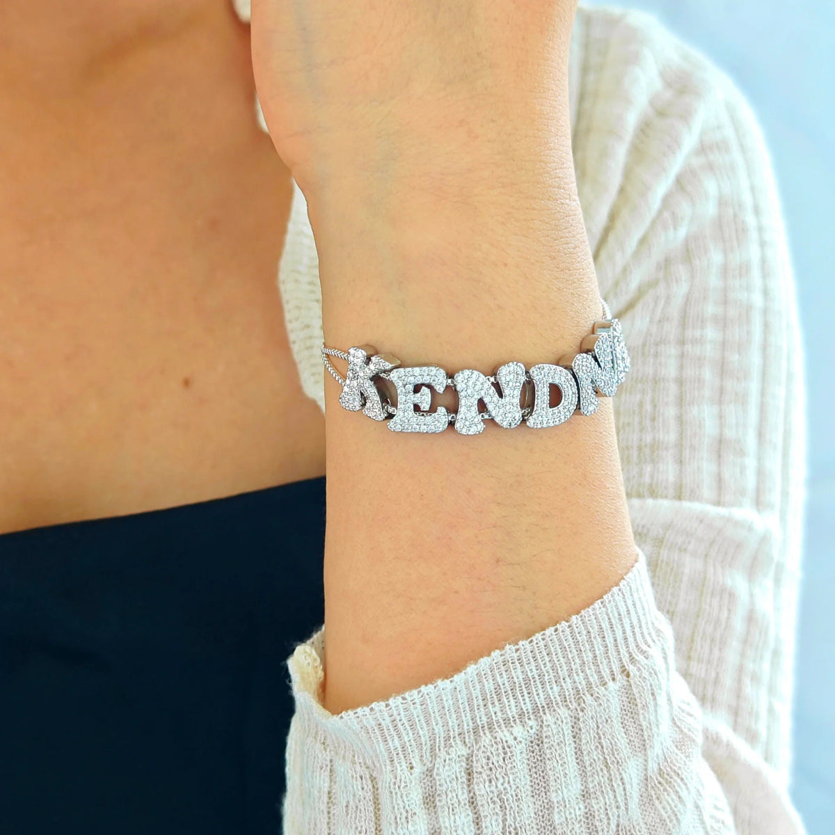 Custom silver-tone alphabet letter slider bracelet with double mesh chain worn on a wrist.