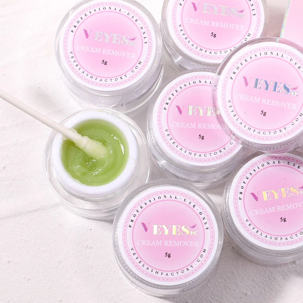 Several small jars of green eyelash extension cream remover arranged on a flat surface.
