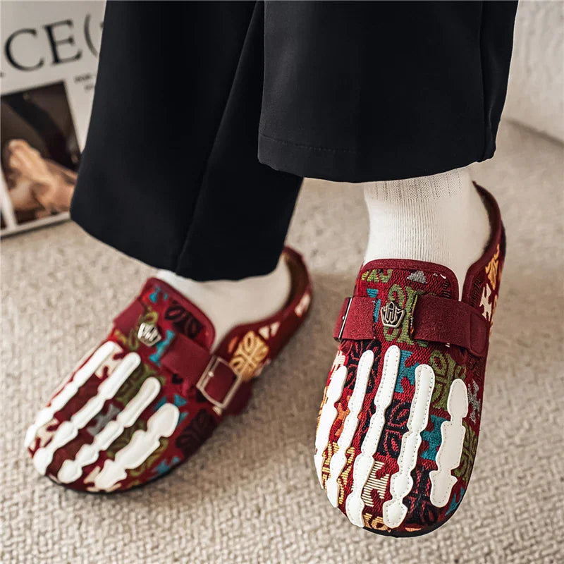 Men's red and multicolored patterned slip-on mule shoes worn with white socks and black trousers