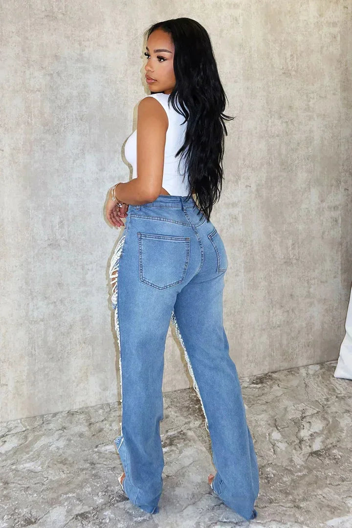 Back view of model in white bodysuit and light blue denim jeans with pearl beaded fringe along the legs