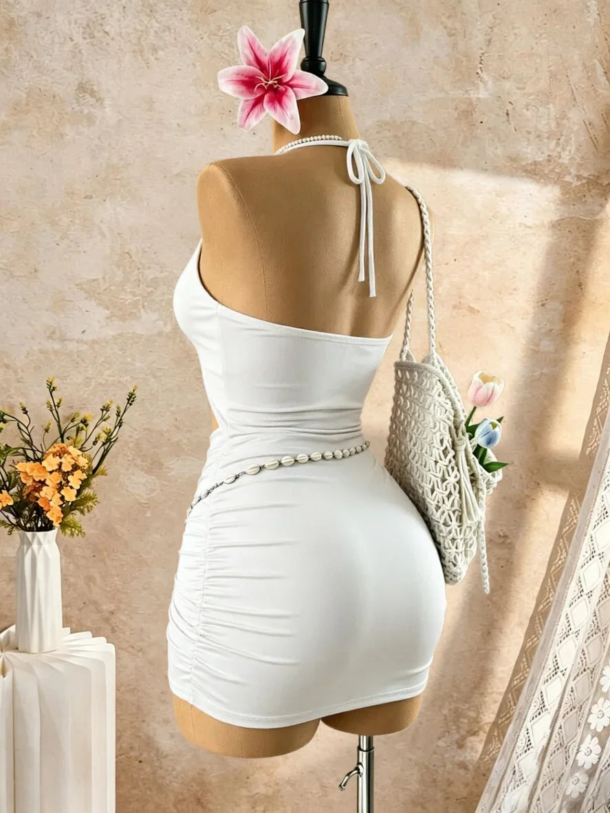 Back view of a white halter neck mini dress with ruched design and waist chain detail on a mannequin