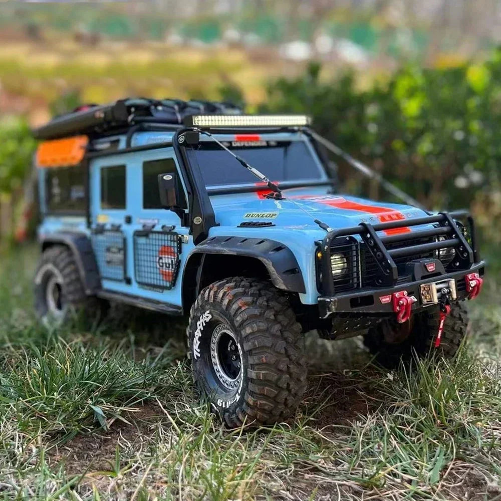 Blue remote control off-road truck with limb riser cables installed, driving on grass