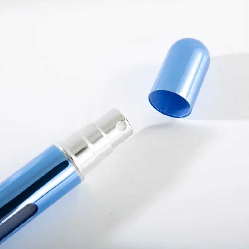 A blue refillable perfume spray bottle with the cap removed.