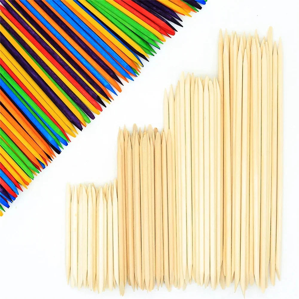 A collection of plain wooden cuticle sticks next to a group of colourful wooden sticks