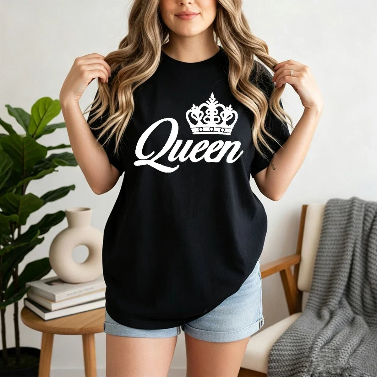 A woman wearing a black short-sleeved t-shirt with a white crown and Queen lettering on the front