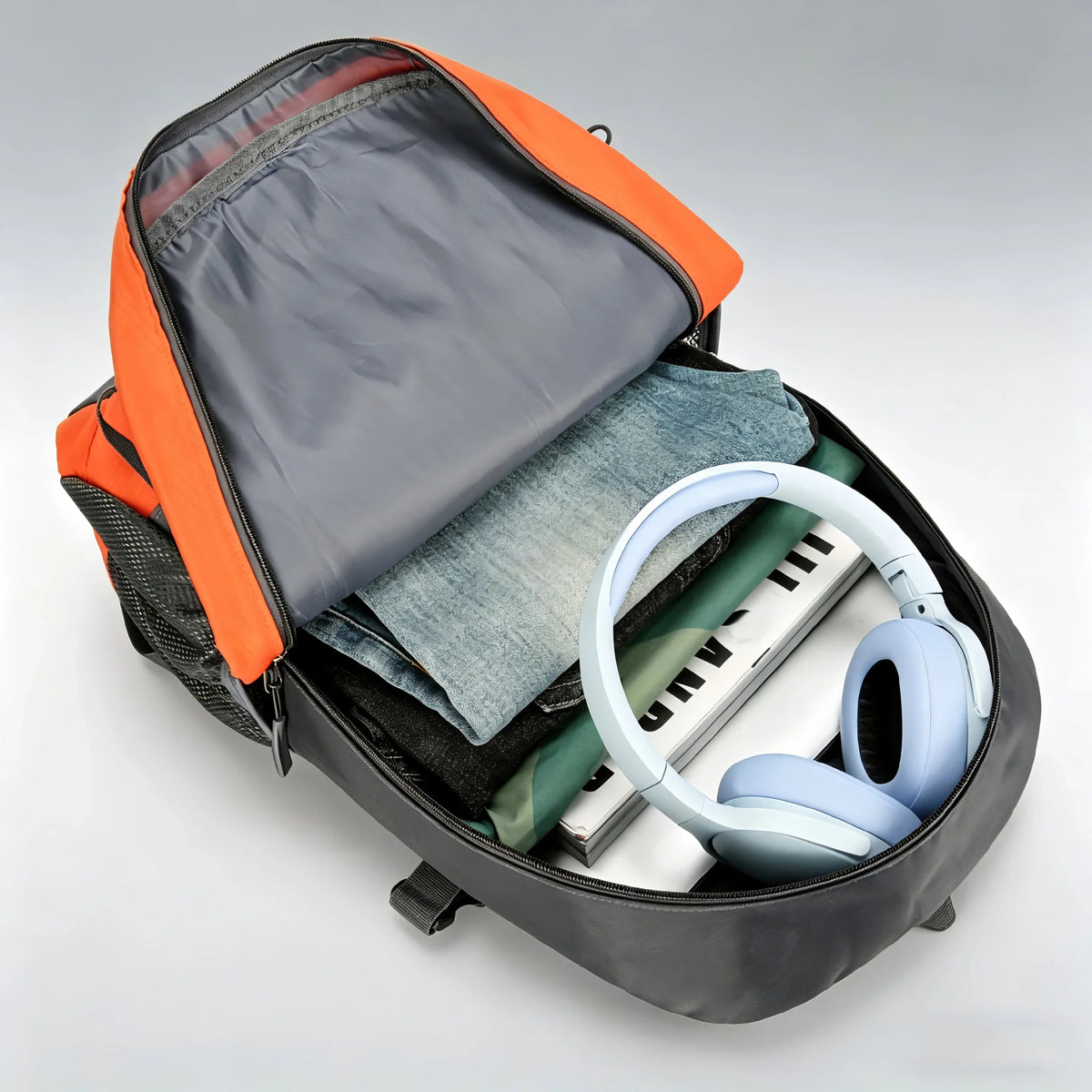 Open orange and grey hiking backpack showing interior with clothes and headphones