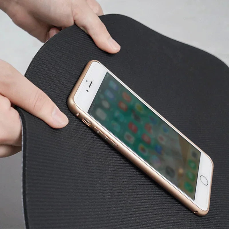 Close up of a black absorbent kitchen mat being held by hands with a smartphone on top.