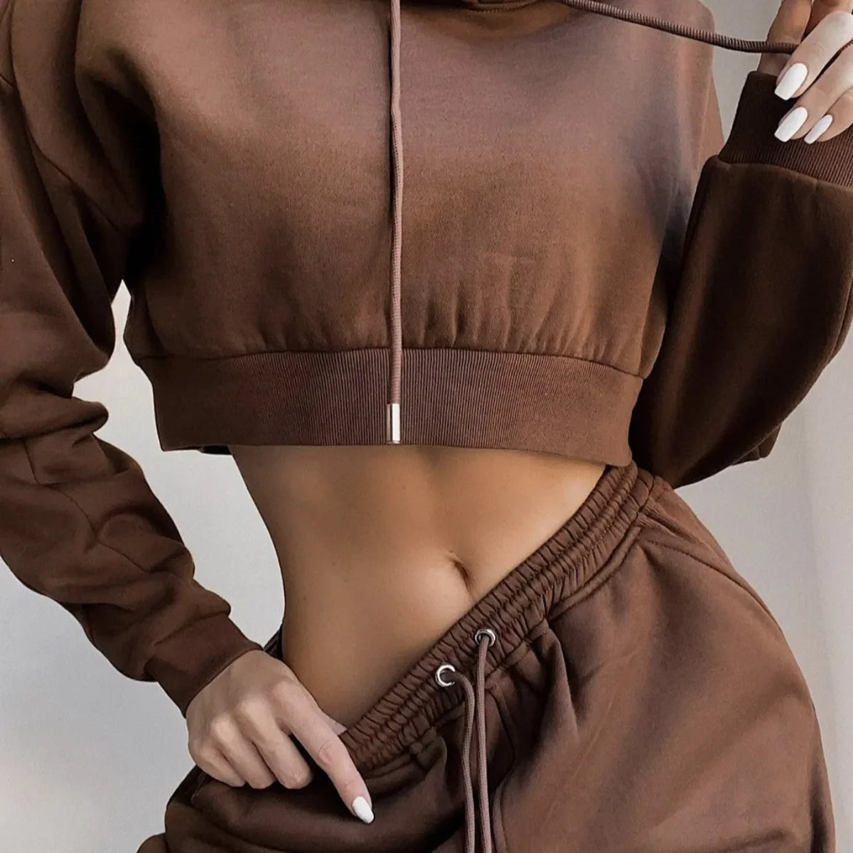 A woman wearing a brown cropped hoodie and matching brown sweatpants jogger set