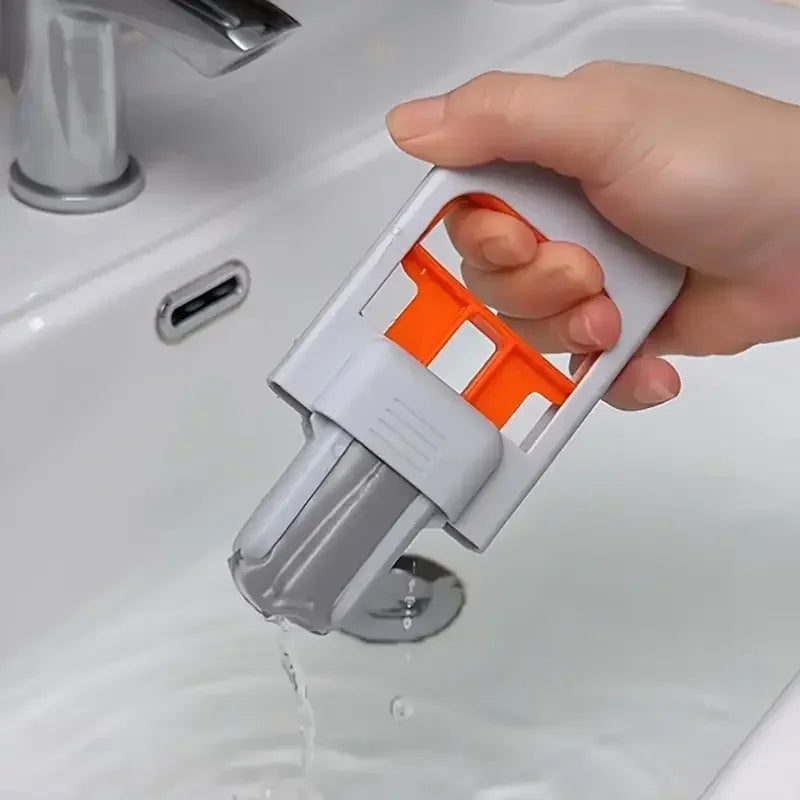 Handheld mini mop in light grey and orange cleaning a bathroom sink