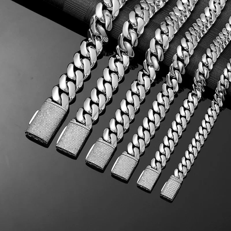 Multiple silver cuban link bracelets of varying widths with diamond clasps
