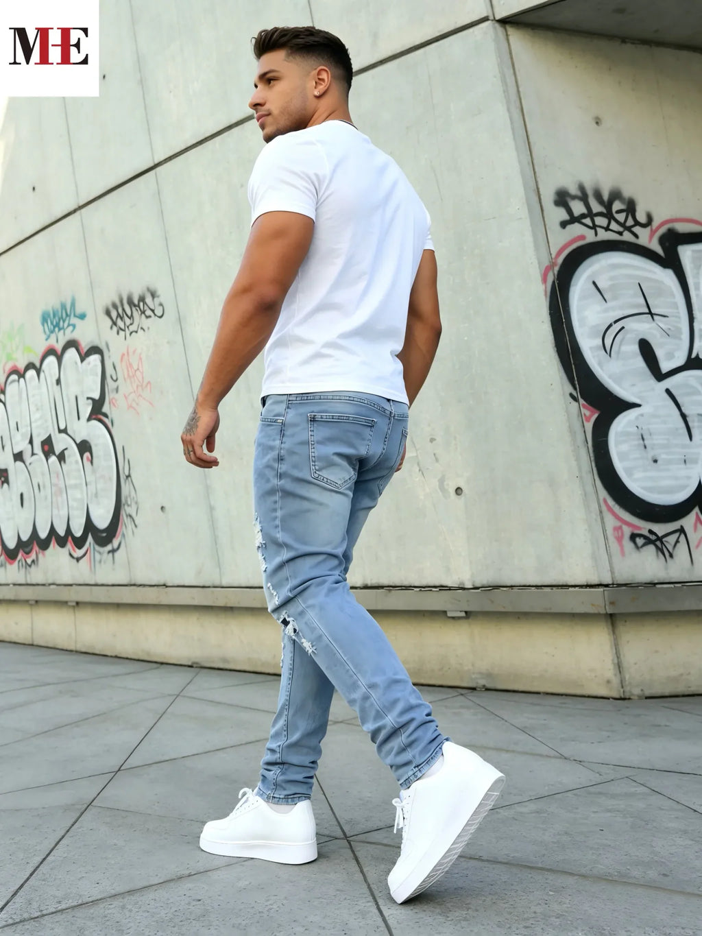 Back view of a man standing in light blue slim fit ripped skinny jeans and white sneakers