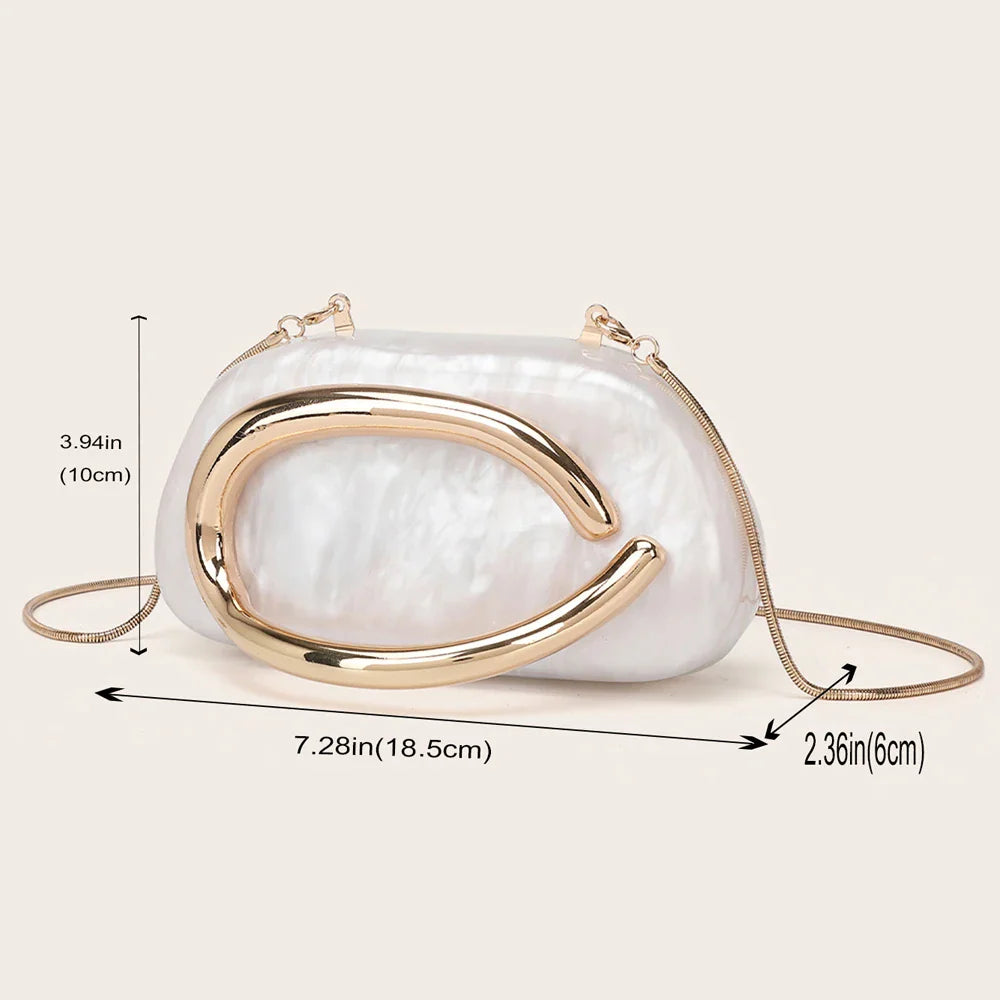 A white marble-effect evening clutch with a gold-tone metallic oval ornament, showing dimensions in inches and centimeters.