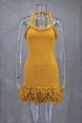 Mustard yellow velvet halter mini dress with braided straps and fringe hem on a mannequin.