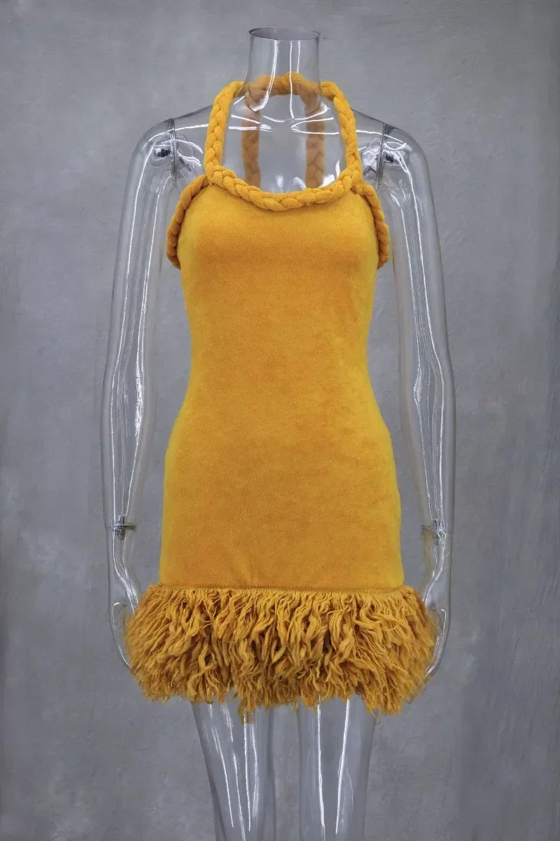 Mustard yellow velvet halter mini dress with braided straps and fringe hem on a mannequin.