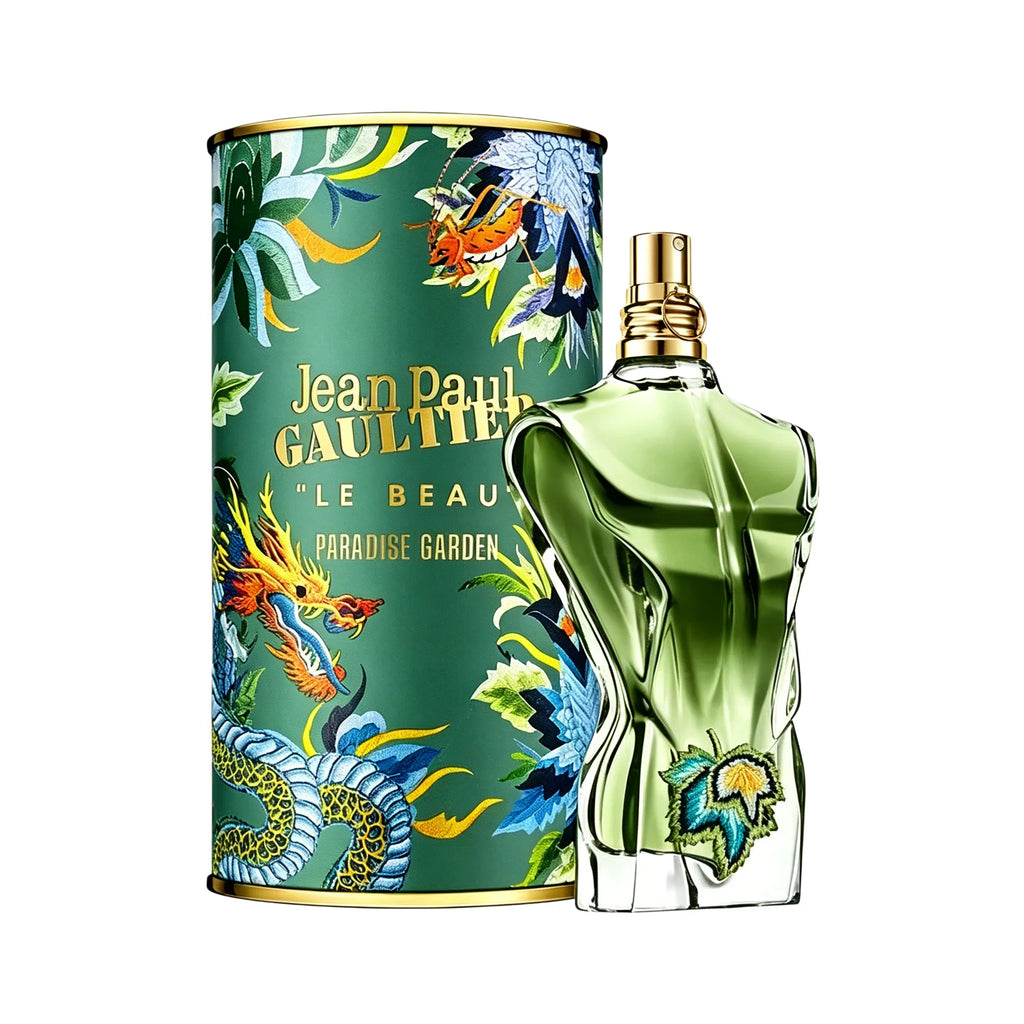 Green torso-shaped glass perfume bottle with leaf embroidery next to a matching patterned cylindrical canister.
