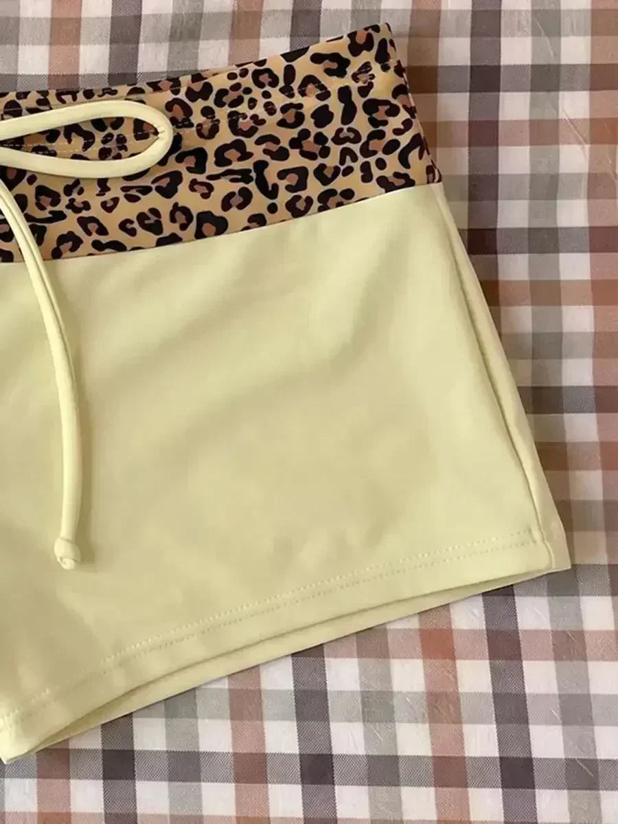 High waisted bikini bottoms featuring a leopard print waistband and pale yellow lower section with drawstring detail