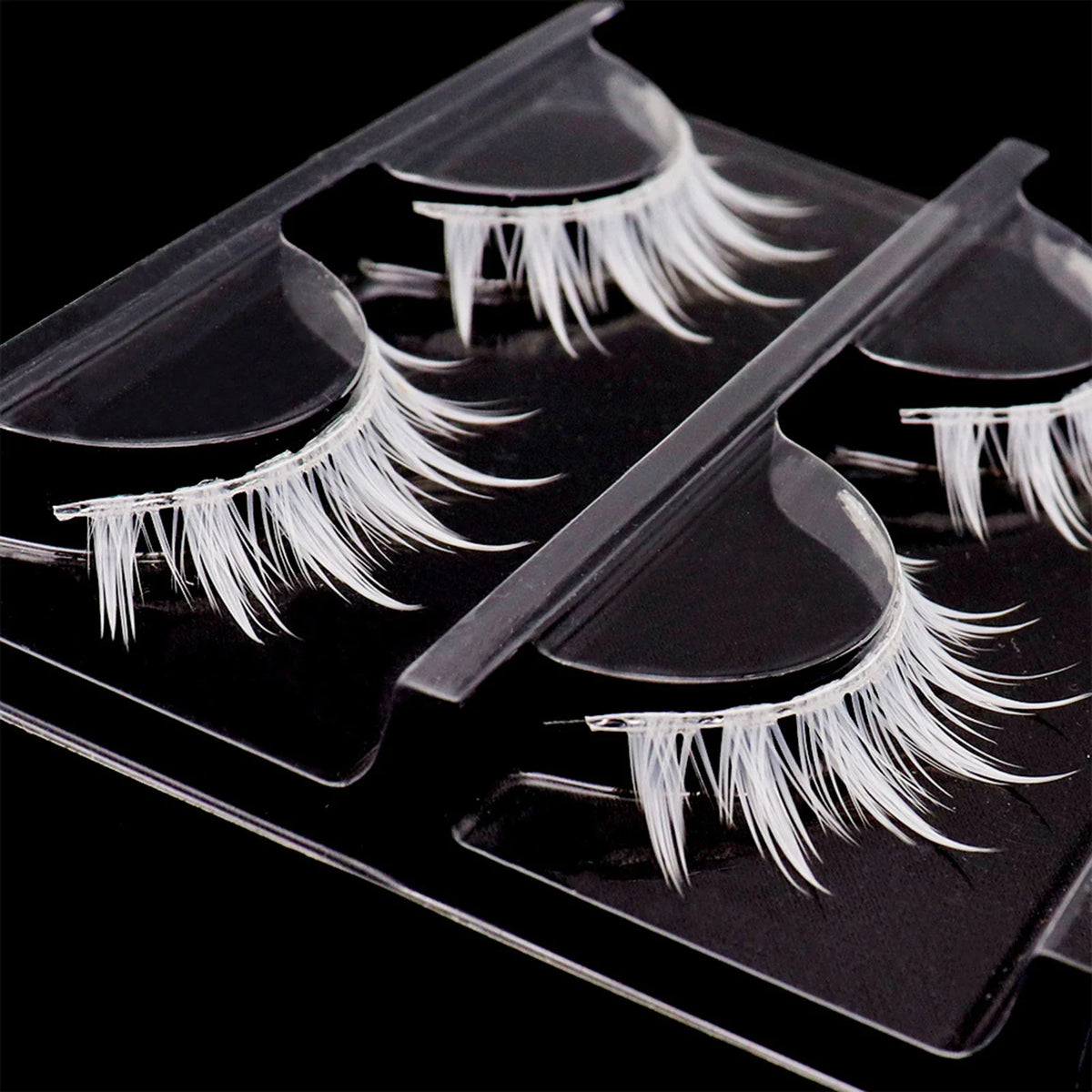 Three pairs of white cluster false eyelashes in a plastic tray