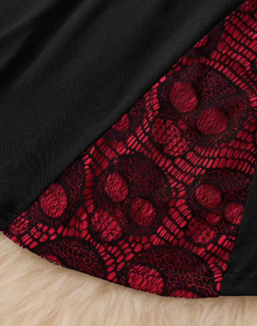 Close-up showing the bottom hem detail of a black dress with red skull lace patchwork.
