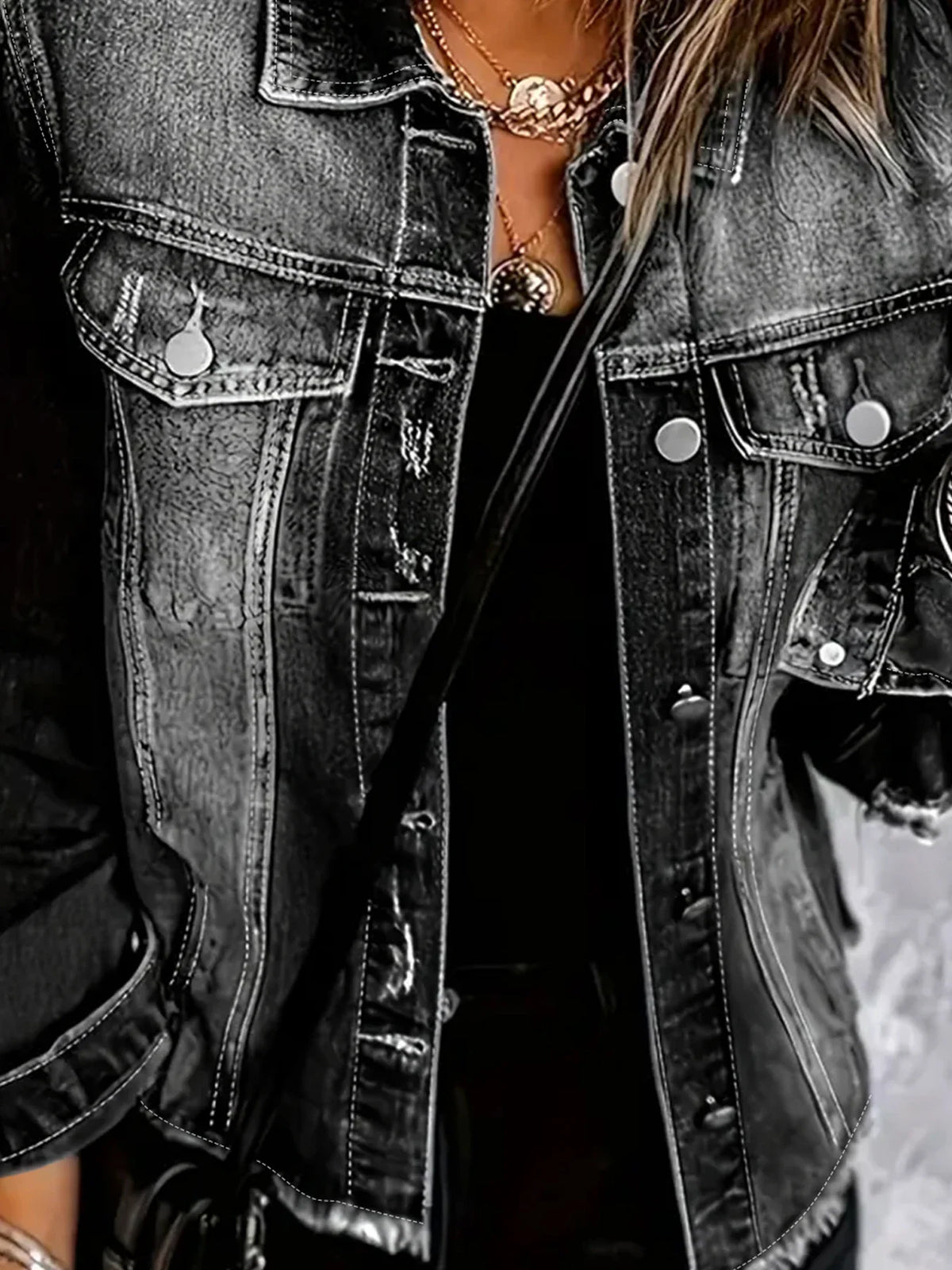 Close-up view of the button detail and fabric texture of a dark grey distressed denim jacket