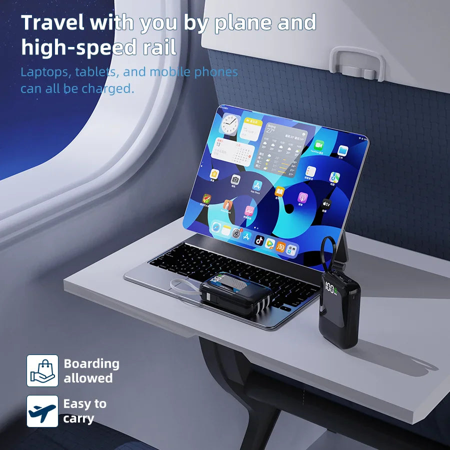 Black power bank charging a tablet on an airplane tray table.