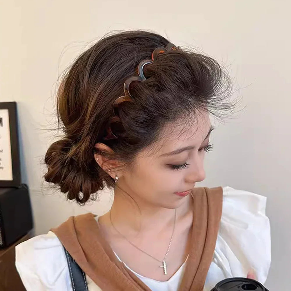 A woman wearing a scalloped tortoise shell pattern hair headband.