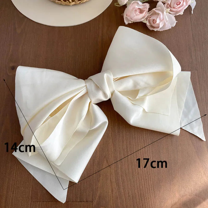 A white satin bow hair clip with measurement lines indicating 14cm by 17cm dimensions