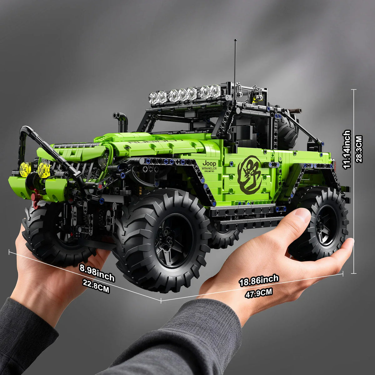 Green building block off-road vehicle model held by hands showing dimensions.