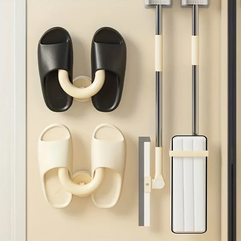 A wall-mounted rack system with hooks holding sandals, a squeegee, and a mop.