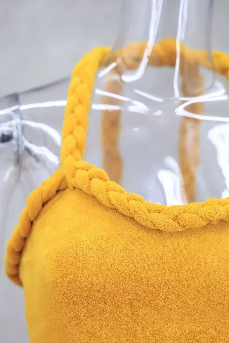 Close-up of the neckline and braided straps of a mustard yellow velvet mini dress.