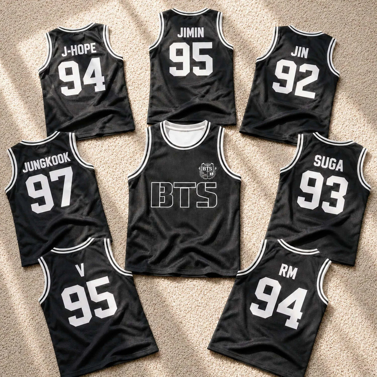 A collection of black basketball jerseys with various band member names and numbers on the back.
