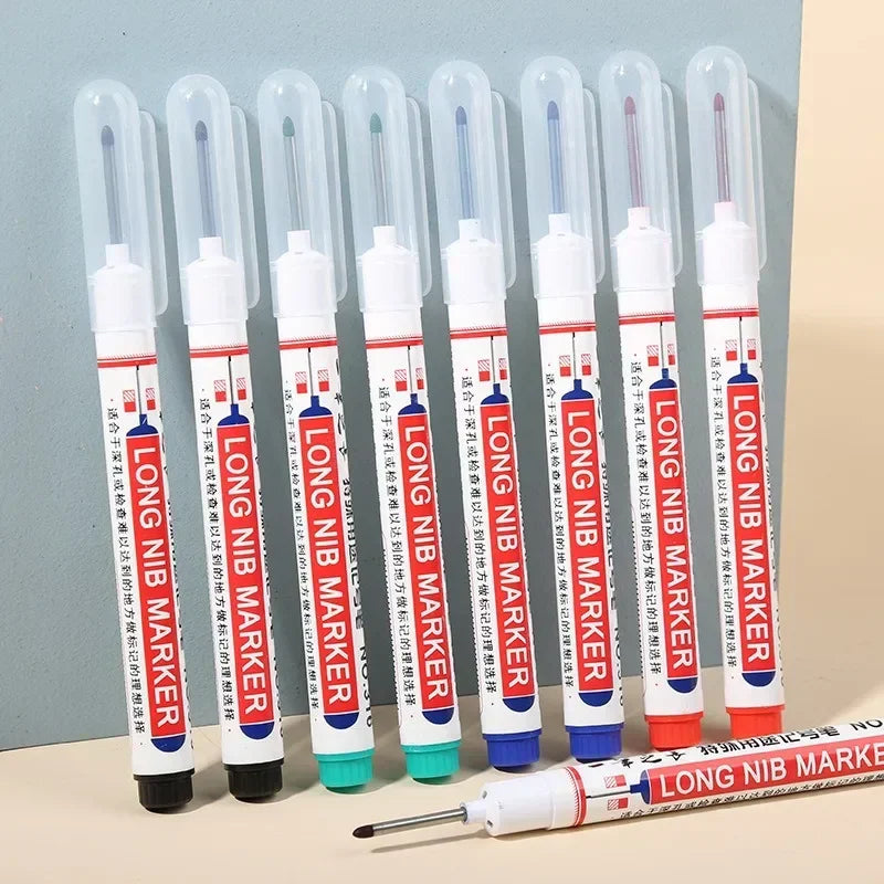 A row of various colored long nib markers with one marker laid horizontally in the foreground.