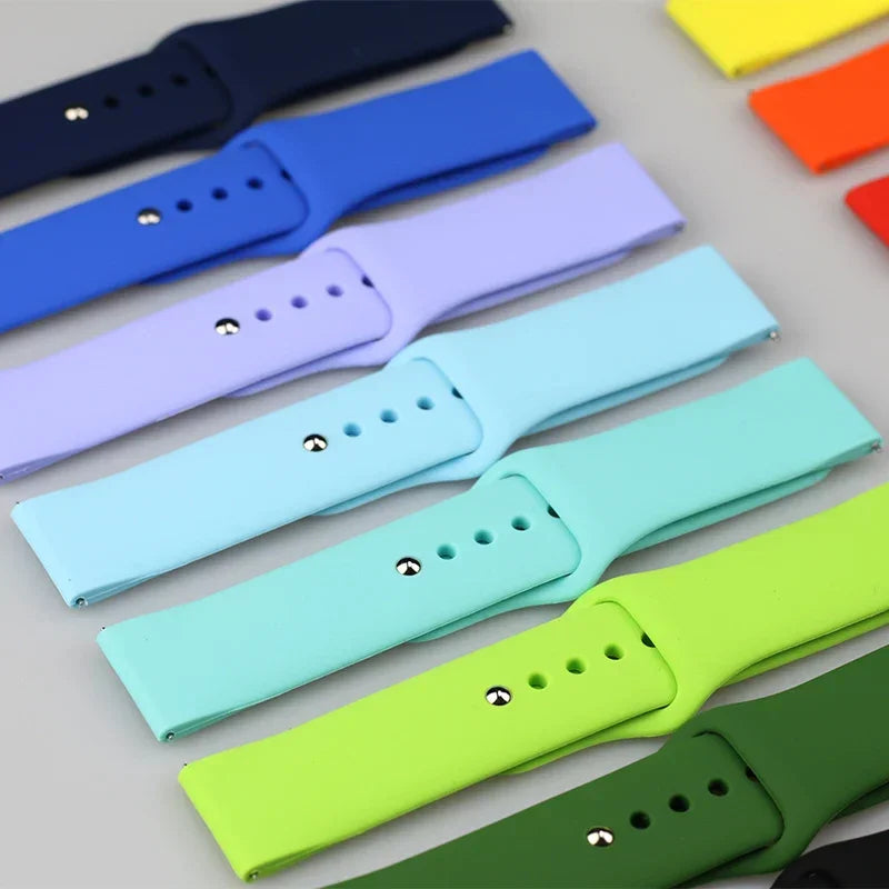 Various colors of silicone watch bands lined up diagonally on a grey background.