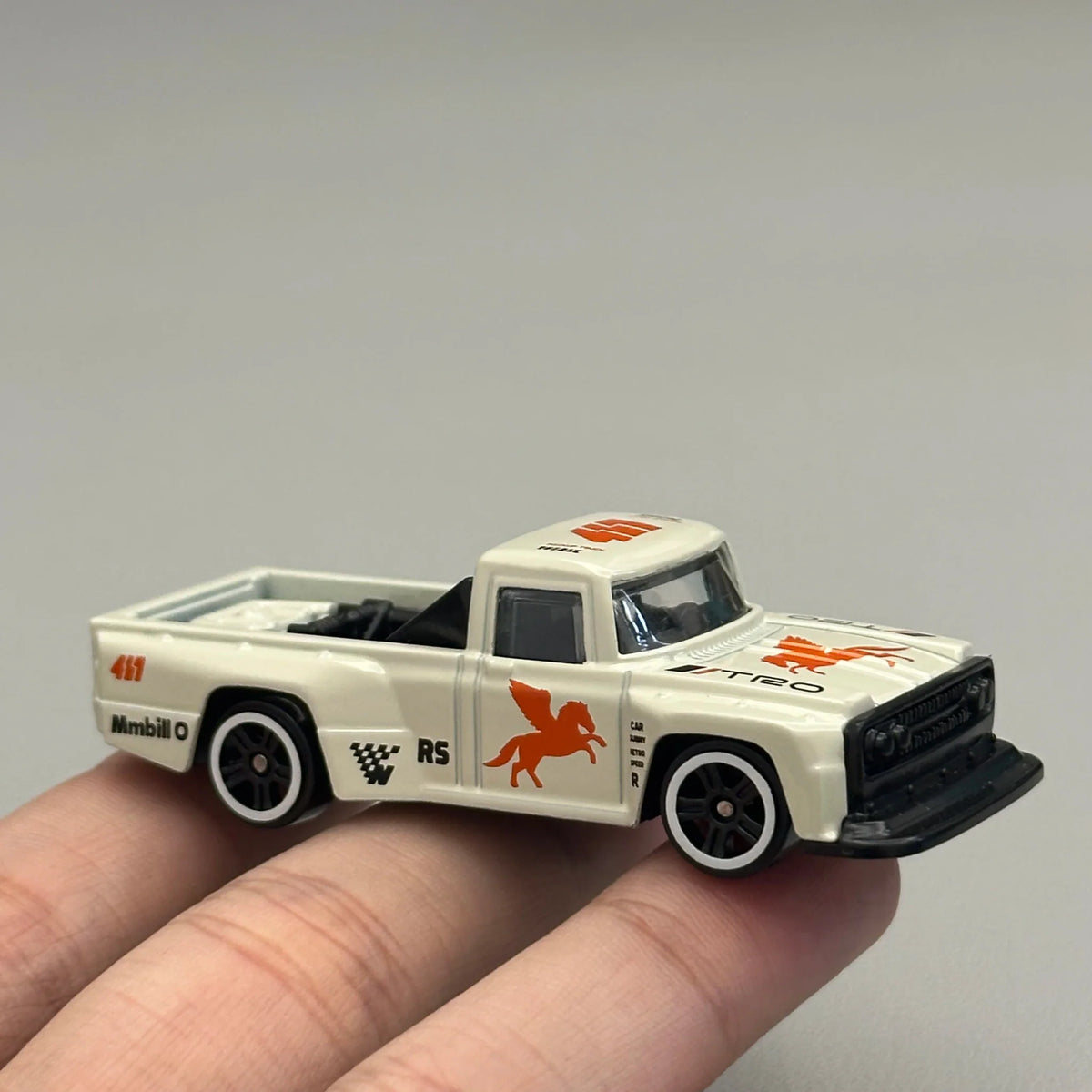 Hand holding a white diecast pickup truck toy model