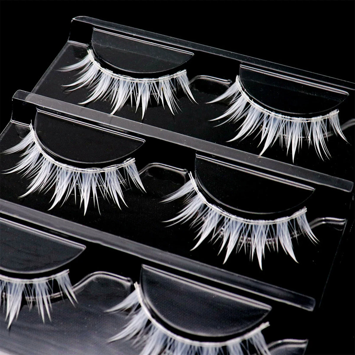 Three pairs of white cosplay false eyelashes in a clear plastic organizer tray