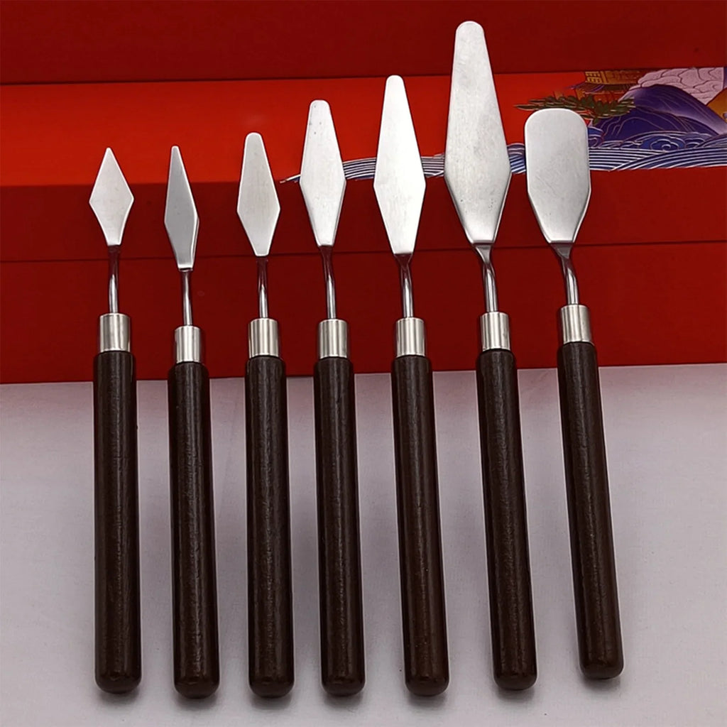 A collection of seven stainless steel artist palette knives with brown wooden handles