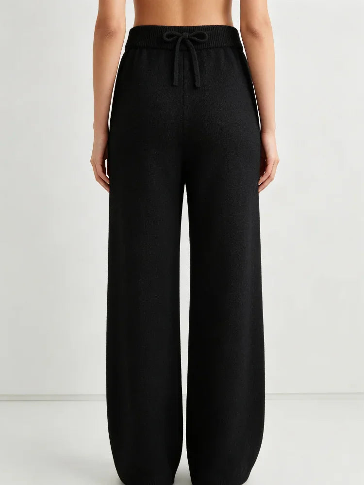 Rear view of high waisted black knit wide leg pants with a drawstring elastic waist, worn by a woman