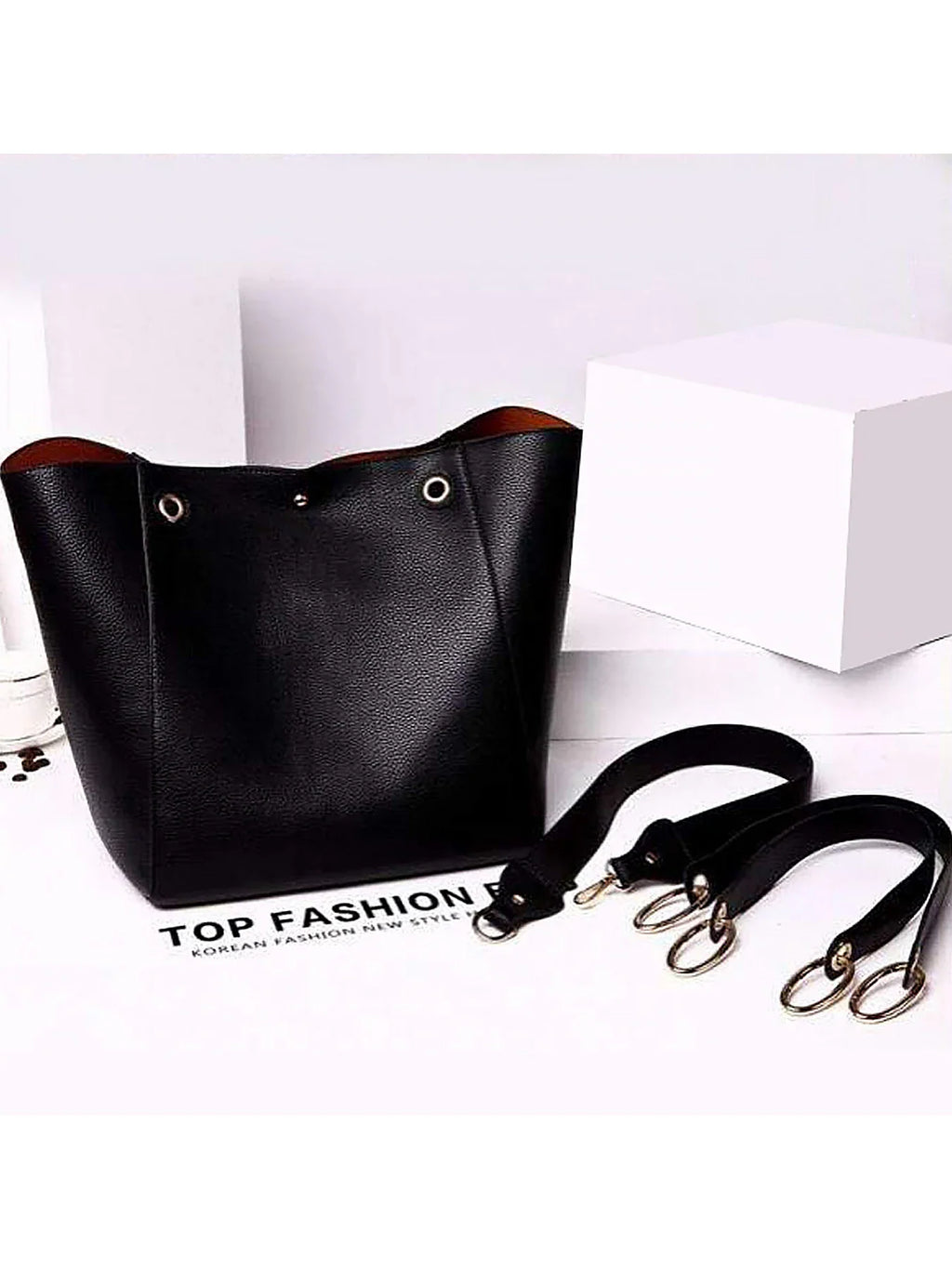 Black tote bag with detachable handles on a white surface