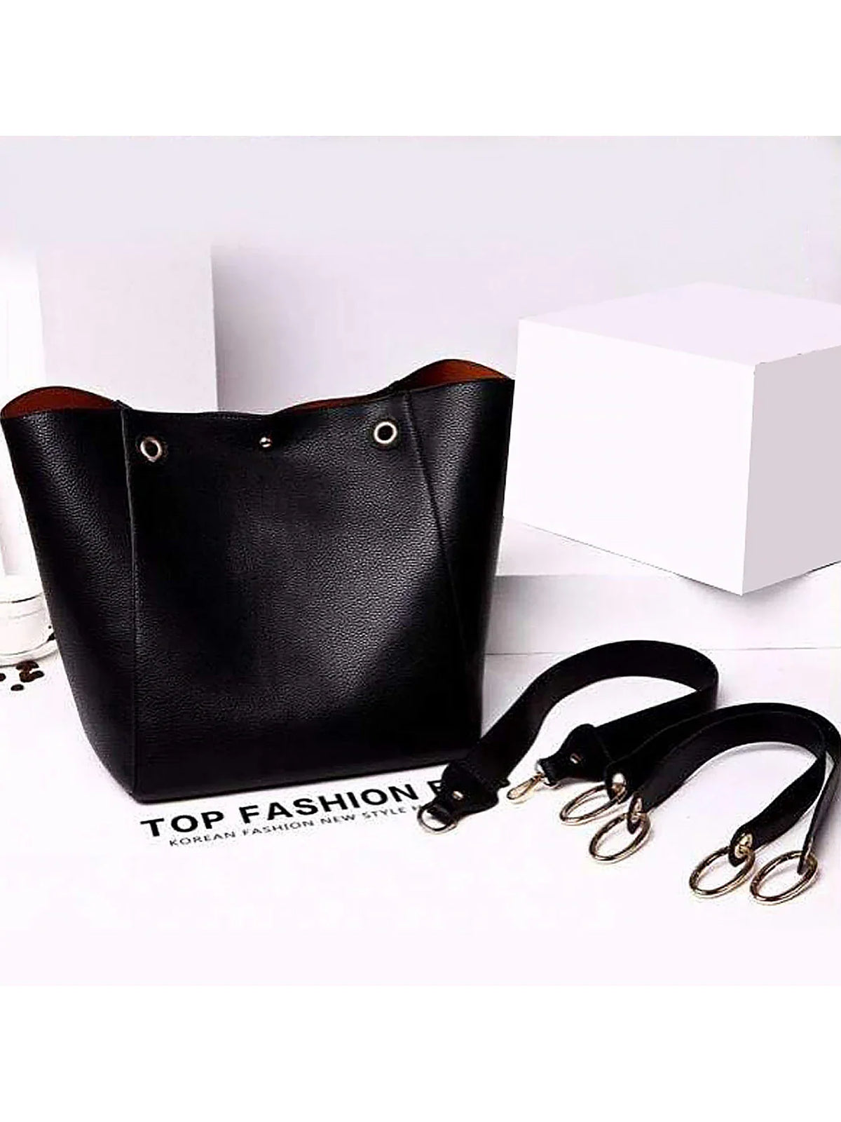 Black tote bag with detachable handles on a white surface