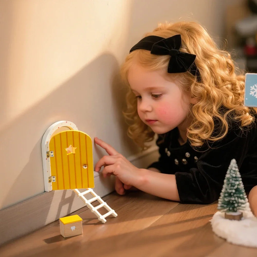 A young girl playing with a miniature wooden fairy door installed on a wall