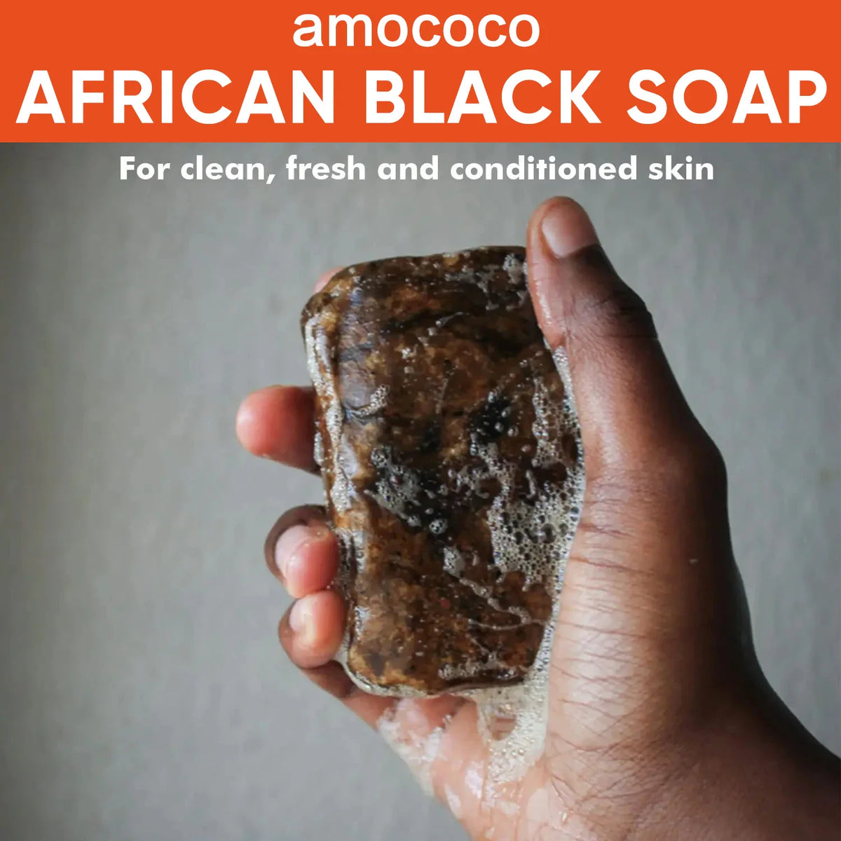 Hand holding a bar of African black soap with lather