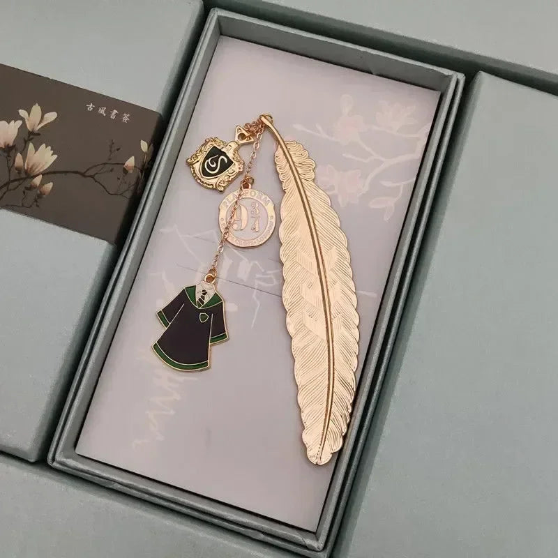 Golden metal feather bookmark with house crest charm and robe pendant in a box