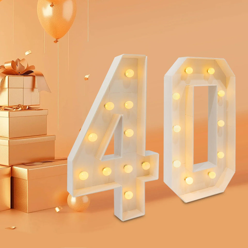 White light-up number 40 standing in a room with gift boxes and a balloon
