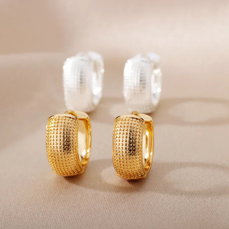 Small gold and silver-toned textured hoop earrings on a neutral background