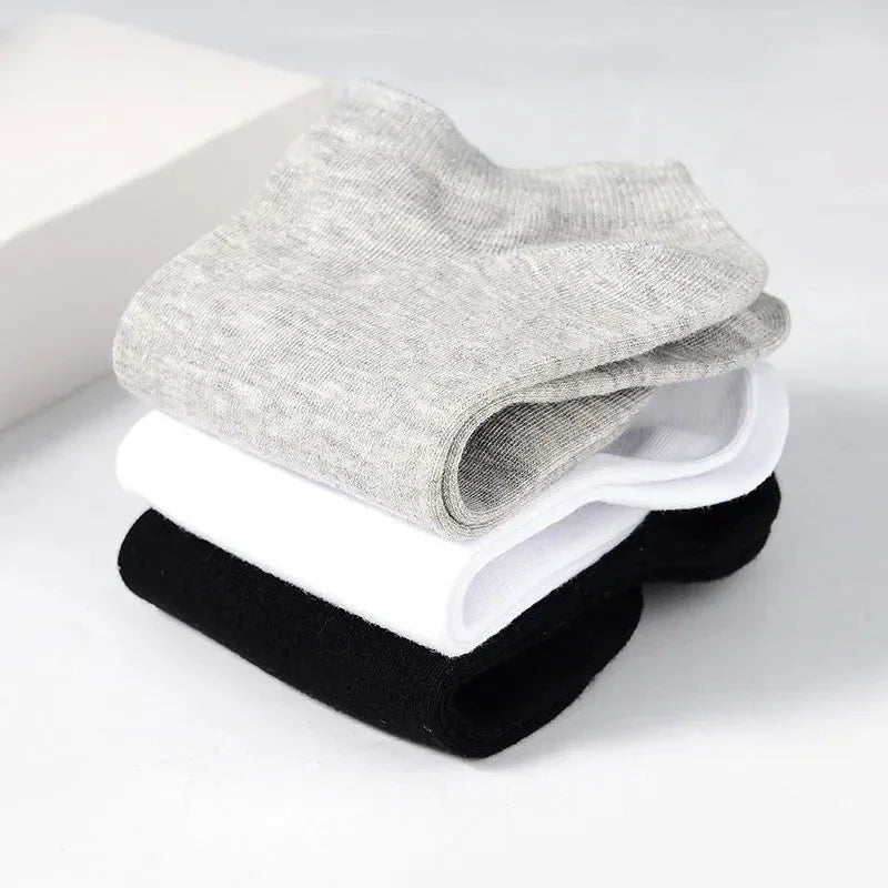 A stacked pile of grey, white, and black low-cut ankle socks.