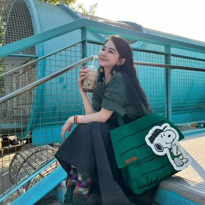 Woman sitting on steps holding a coffee while carrying a green canvas tote bag