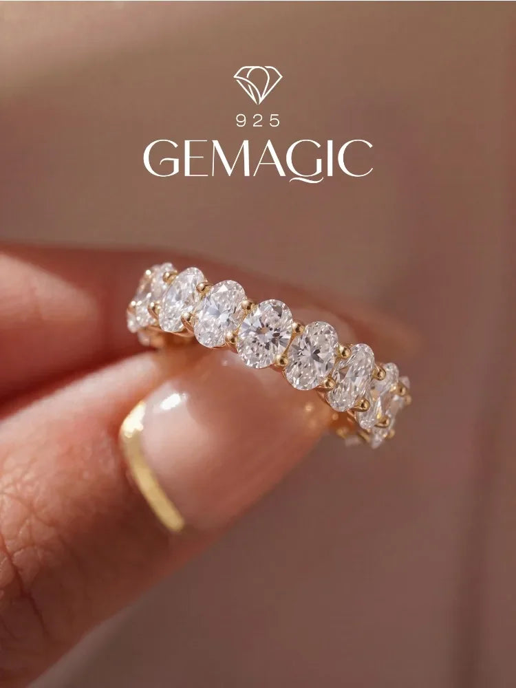 Eternity band ring featuring oval-cut white zircon stones set in gold-plated sterling silver, worn on a finger.