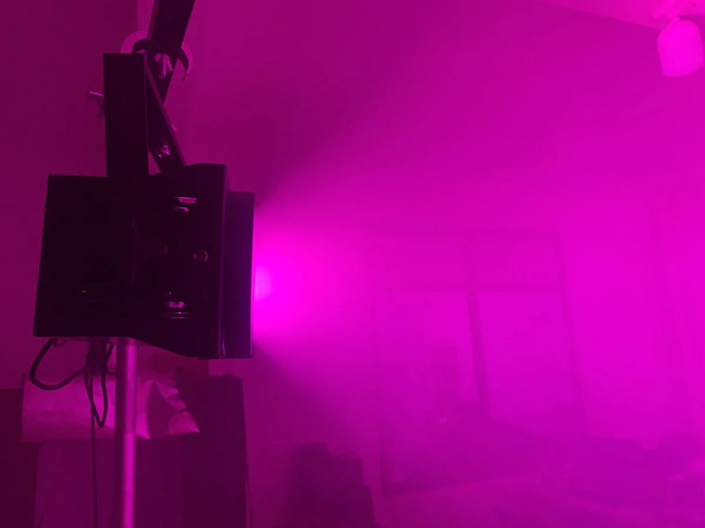 Black stage blinder light emitting a vibrant pink wash beam in a dark room