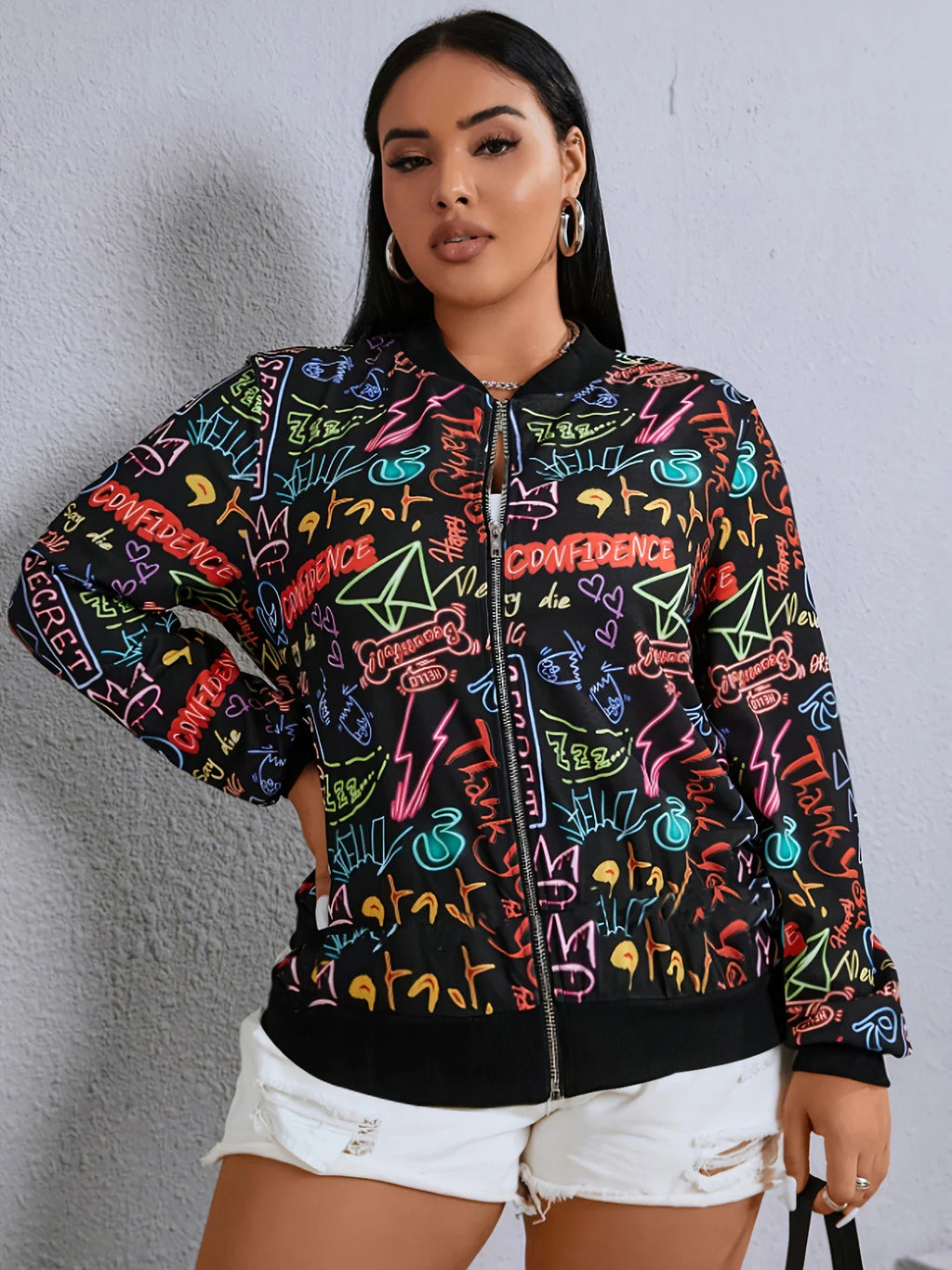 Plus size woman posing in a black zip-up bomber jacket featuring a vibrant neon graffiti design.