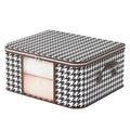 A portable black and white houndstooth patterned fabric storage bin with side handles and a zipper closure